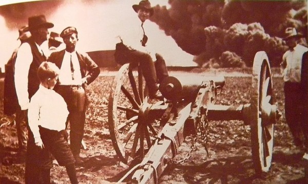 Cannon used to fight burning oil tanks in distance.