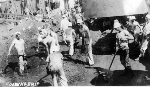 USS Texas at coaling barge as sailor shovel tons of coal.